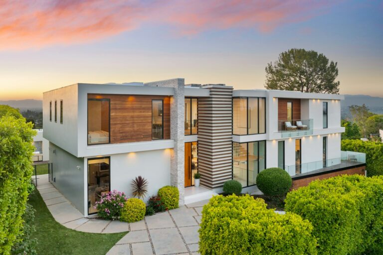 Contemporary two-level home on hillside with shrubs and trees